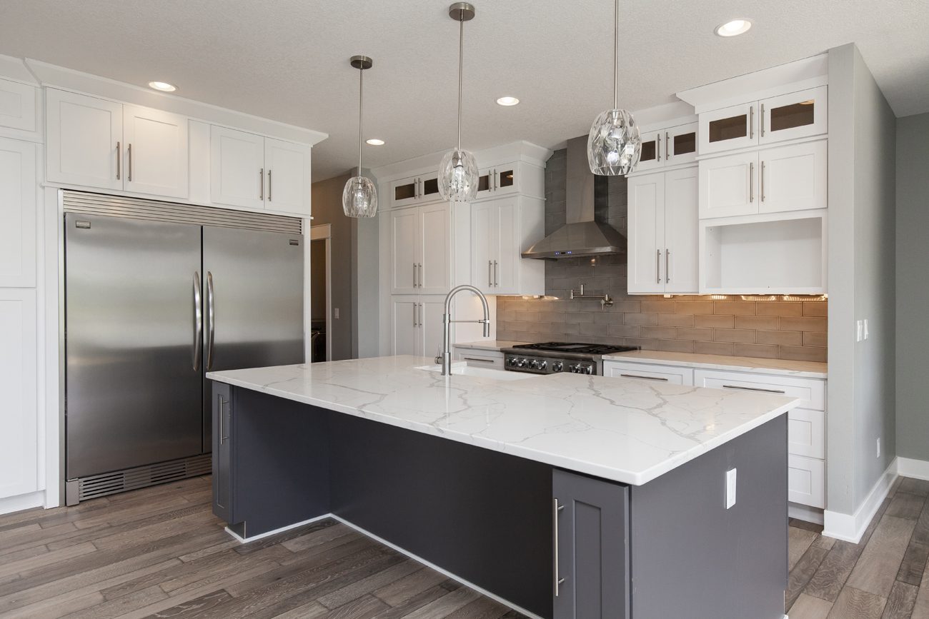 IMG_7052 Modern kitchen with white cabinetry, stainless steel appliances, and a central island with a marble countertop.